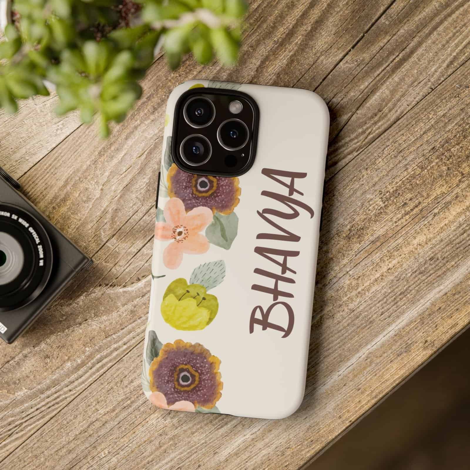 Bright floral phone case with personalized name "BHAVYA" on a wooden surface, ideal for iPhone models.