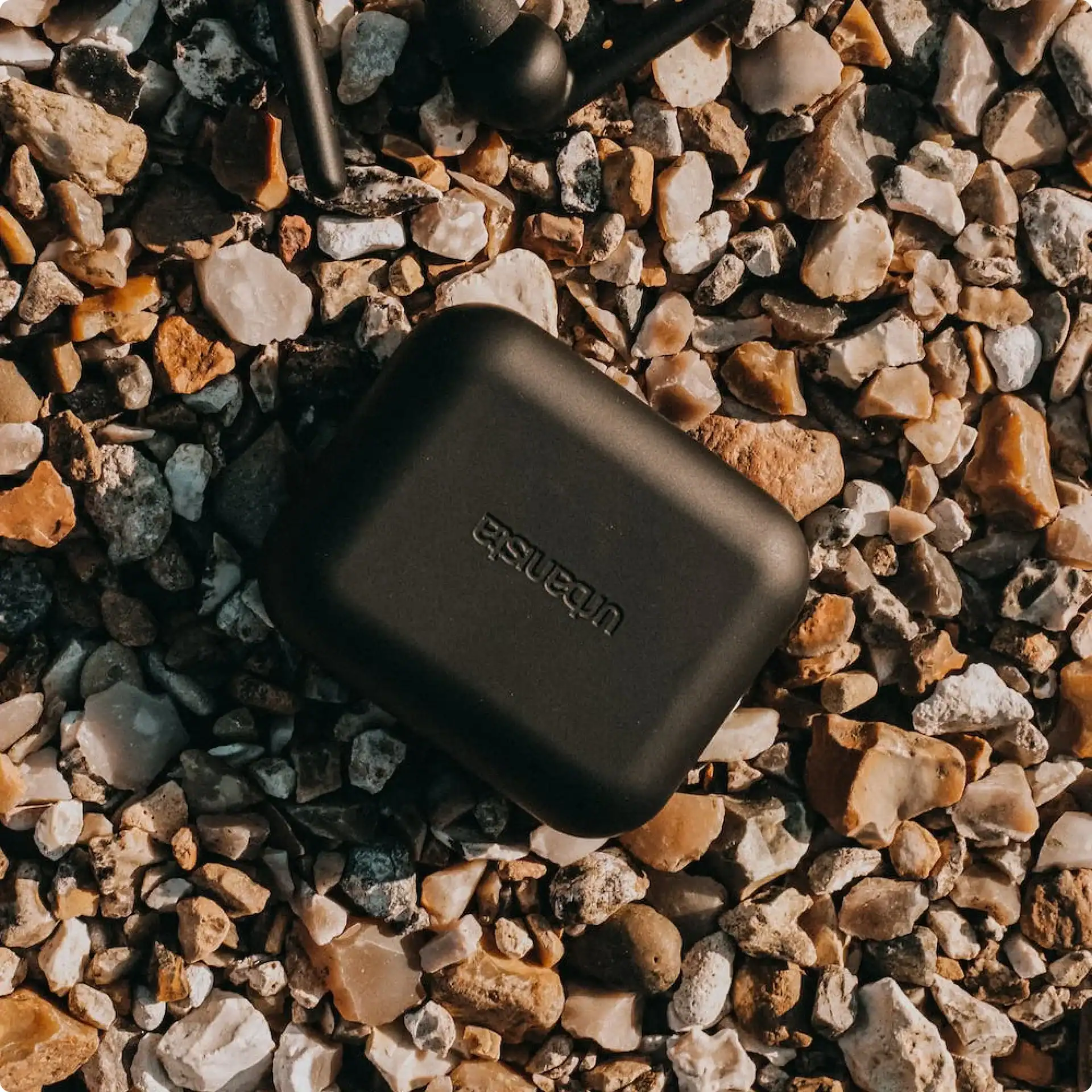 Wireless earbuds case on gravel surface.