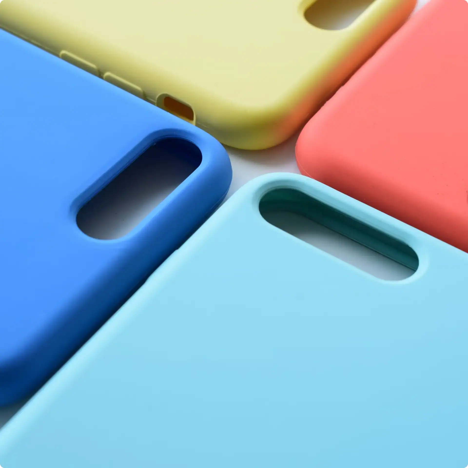 Colorful silicone phone cases in yellow, pink, blue, and teal for smartphones.