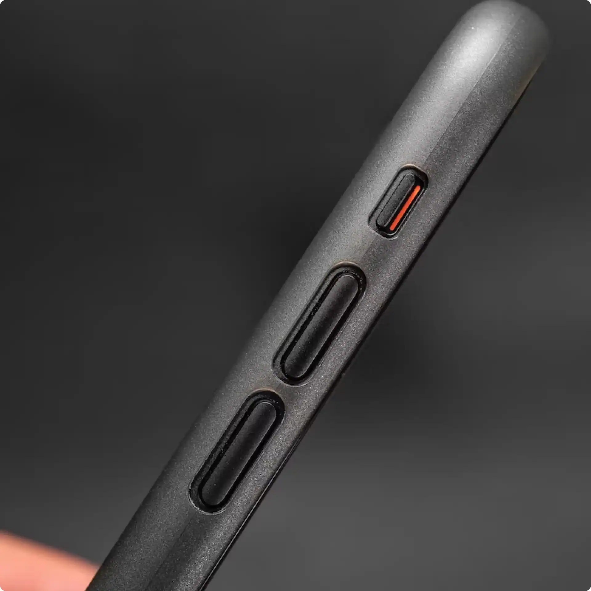 Slim black phone case side buttons with orange accents on a dark background.